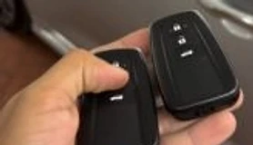 Chaves automotivas em mãos ao lado de veículo
