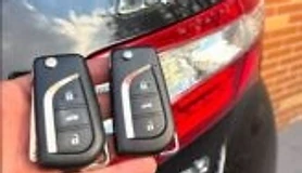 Chaves automotivas em mãos ao lado de veículo